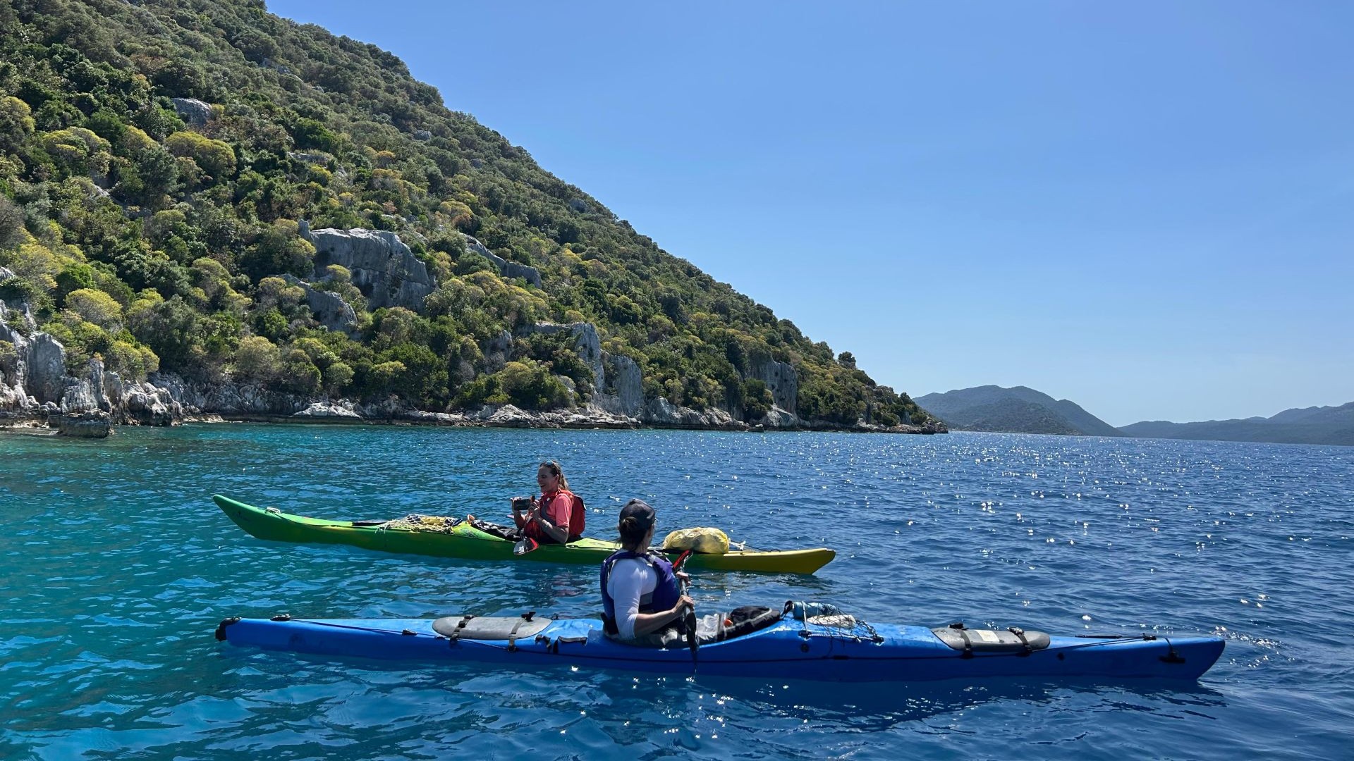 Kekova Üçağız’da berrak denizde deniz kanosu (kayak) turu yapan iki kişi, Akdeniz’in doğal güzellikleriyle çevrili